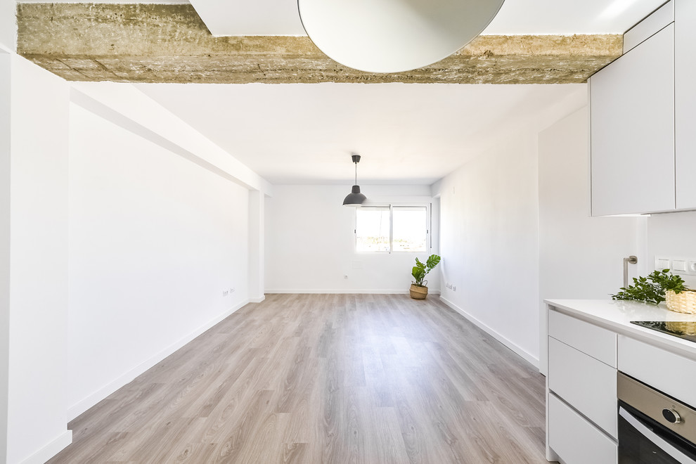 Imagen de salón abierto contemporáneo de tamaño medio con paredes blancas, suelo laminado y suelo marrón