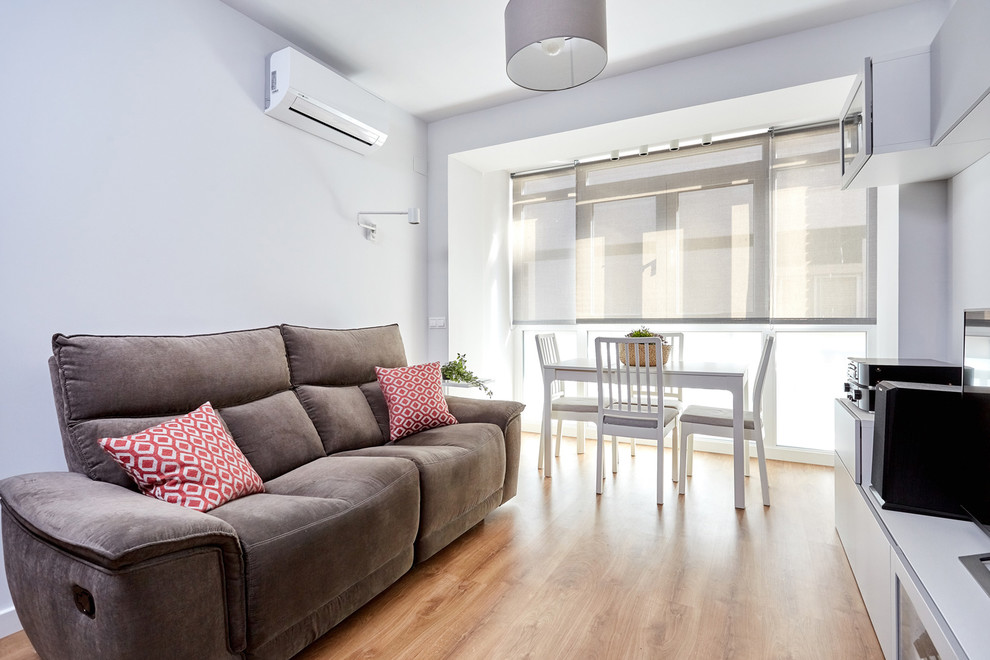 Mittelgroßes, Abgetrenntes Nordisches Wohnzimmer mit grauer Wandfarbe, Laminat, freistehendem TV und braunem Boden in Sonstige