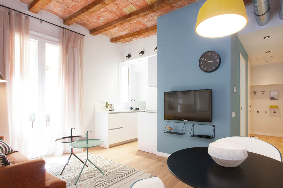 Ejemplo de salón abierto minimalista pequeño con paredes azules, suelo de madera en tonos medios y televisor colgado en la pared