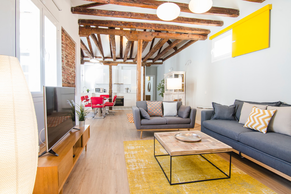 Mittelgroßes, Offenes Modernes Wohnzimmer ohne Kamin mit hellem Holzboden, freistehendem TV und grauer Wandfarbe in Madrid
