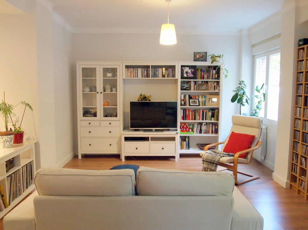 Example of a mid-sized danish open concept medium tone wood floor living room library design in Madrid with beige walls, no fireplace and a media wall