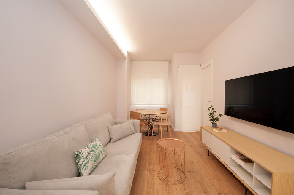 Foto di un soggiorno scandinavo di medie dimensioni e aperto con pareti bianche, pavimento in legno massello medio, nessun camino, TV a parete e pavimento marrone