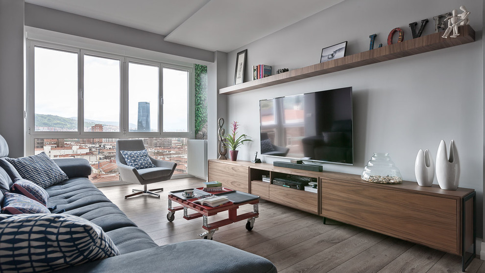 Идея дизайна: изолированная, парадная гостиная комната среднего размера в современном стиле с серыми стенами, темным паркетным полом, телевизором на стене и серым полом без камина
