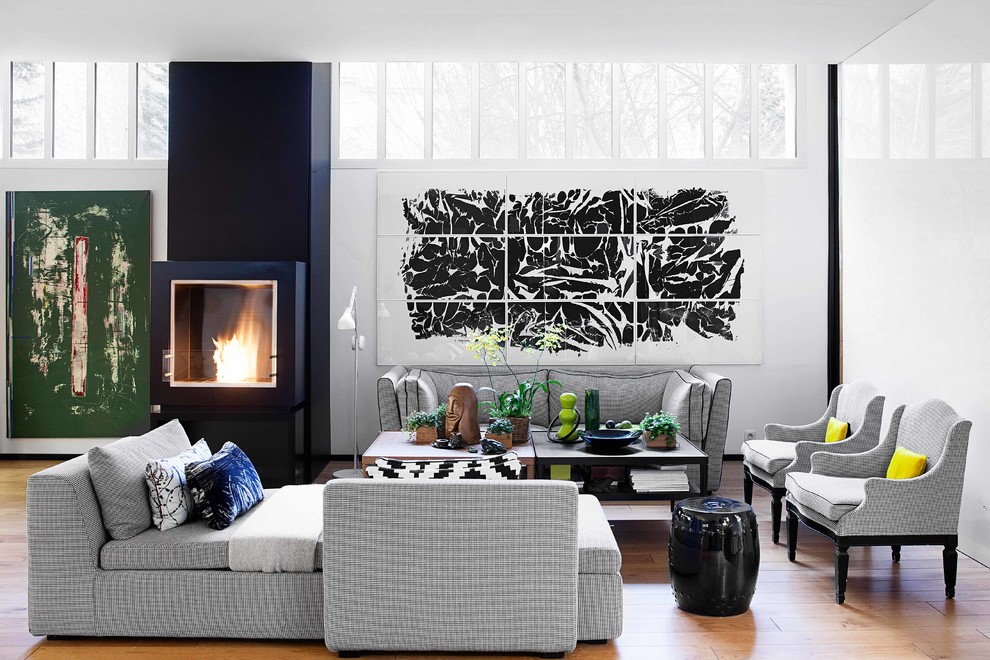 Cette photo montre un salon tendance avec un mur blanc, un sol en bois brun, une cheminée standard, un sol marron et éclairage.