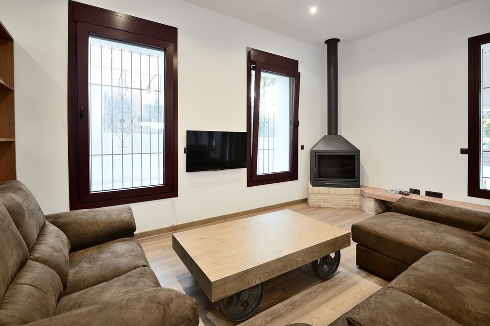 Ejemplo de salón abierto de estilo de casa de campo de tamaño medio con suelo de madera en tonos medios, chimenea de esquina y marco de chimenea de metal