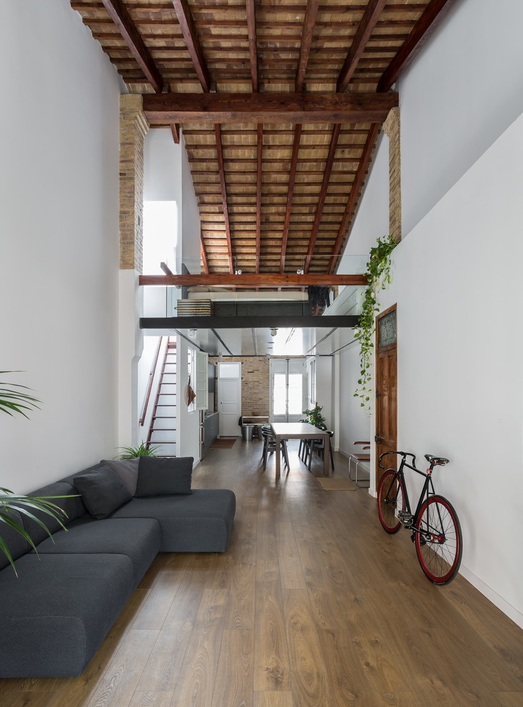 Repräsentatives, Fernseherloses, Offenes, Mittelgroßes Industrial Wohnzimmer ohne Kamin mit weißer Wandfarbe und braunem Holzboden in Valencia