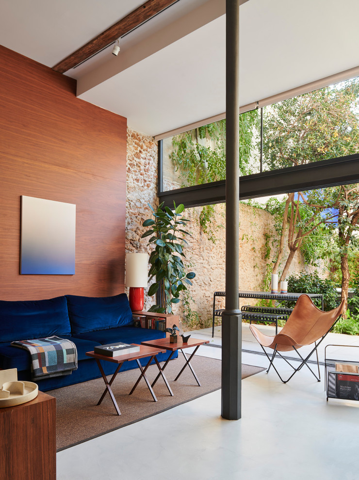 На фото: двухуровневая гостиная комната среднего размера в современном стиле с коричневыми стенами, бетонным полом, отдельно стоящим телевизором, серым полом и панелями на стенах с