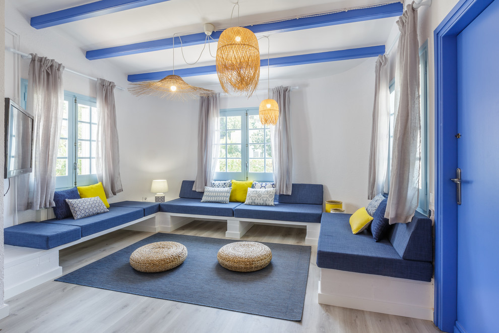 Diseño de salón para visitas cerrado costero con paredes blancas, suelo de madera clara, televisor colgado en la pared y suelo gris