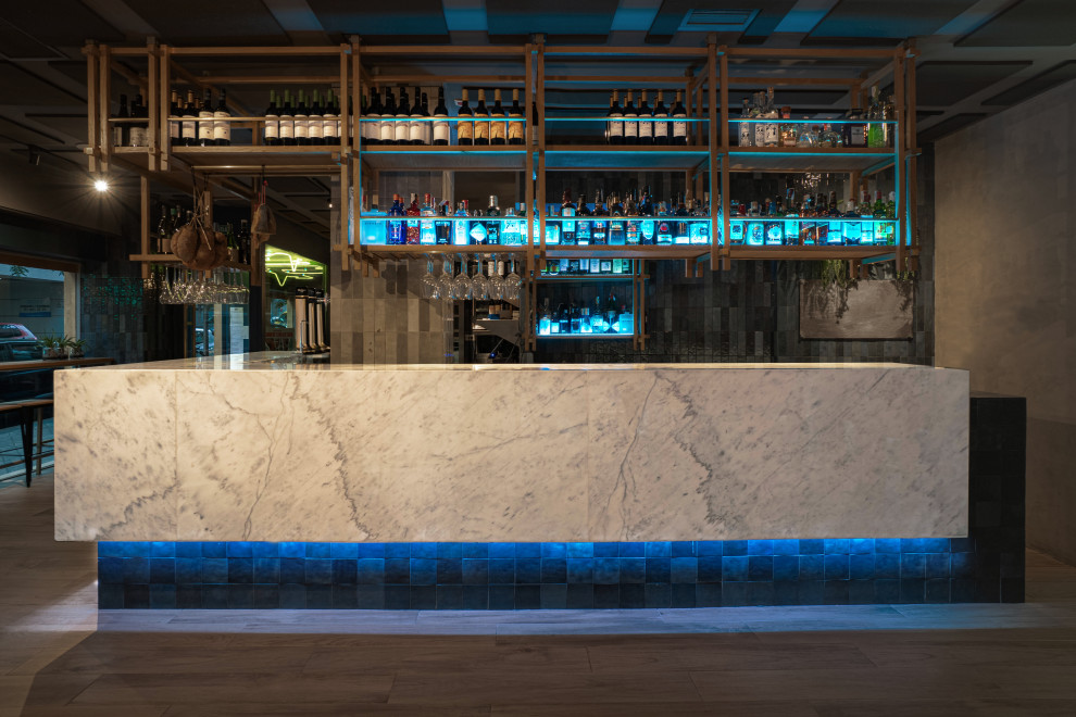 Diseño de salón con barra de bar abierto mediterráneo grande con paredes azules, suelo de madera en tonos medios y suelo marrón