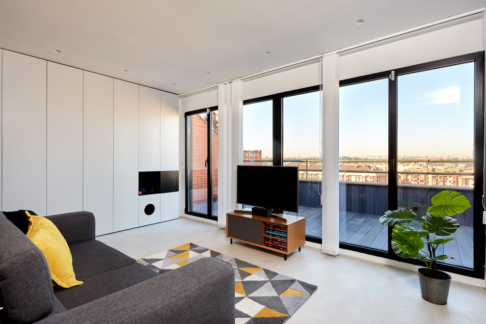 Foto på ett mellanstort nordiskt allrum med öppen planlösning, med grå väggar, betonggolv, en fristående TV och grått golv