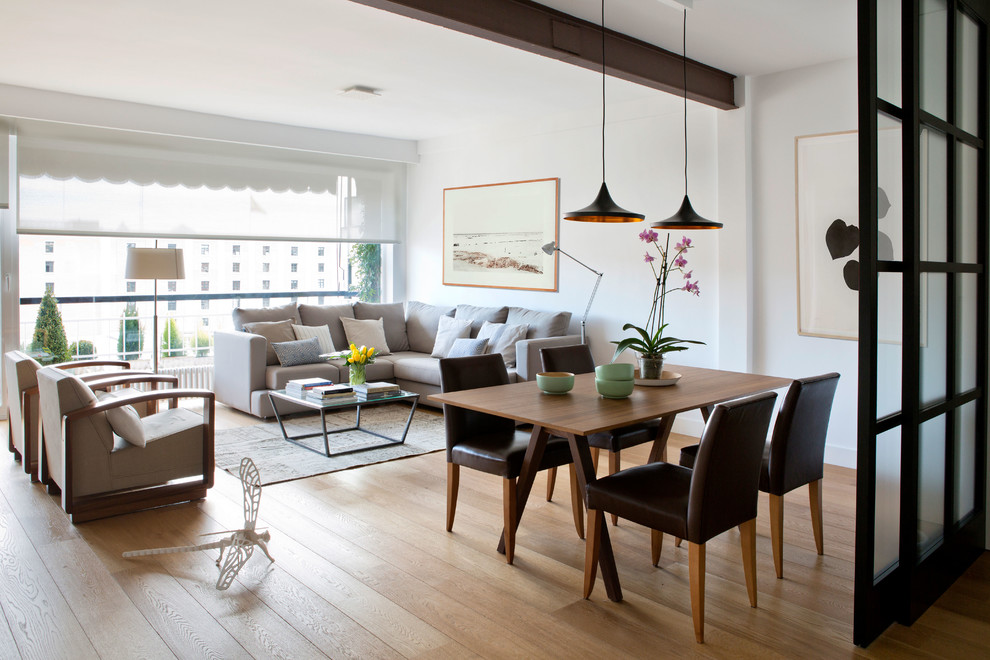 Mittelgroßes, Repräsentatives, Offenes, Fernseherloses Modernes Wohnzimmer ohne Kamin mit weißer Wandfarbe und braunem Holzboden in Madrid