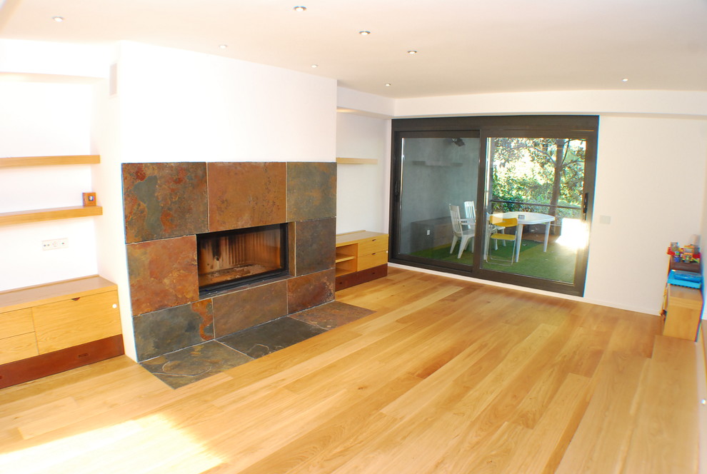Diseño de salón actual con suelo de madera clara, chimenea lineal y marco de chimenea de piedra