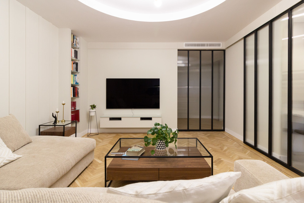 Diseño de salón contemporáneo con paredes grises, suelo de madera clara y televisor colgado en la pared