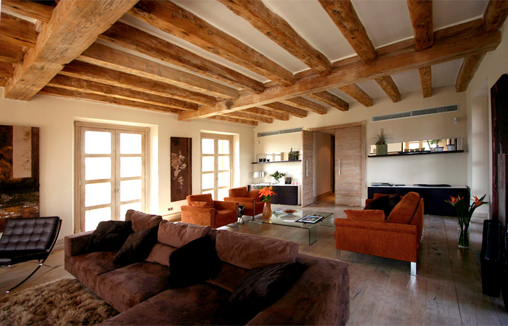Diseño de salón abierto rural grande con paredes beige, suelo de madera clara, suelo beige y televisor independiente