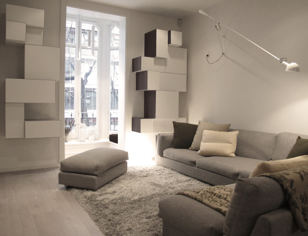 Cette photo montre un salon tendance de taille moyenne avec un mur gris, parquet clair, un téléviseur fixé au mur et un sol gris.