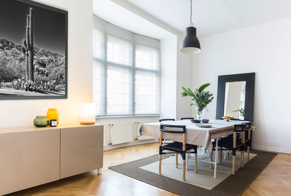 Diseño de comedor nórdico grande con paredes blancas y suelo de madera en tonos medios