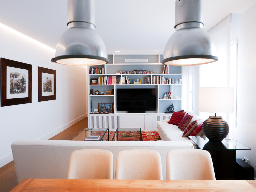 Imagen de biblioteca en casa abierta ecléctica de tamaño medio con paredes blancas, suelo de madera en tonos medios, pared multimedia y suelo marrón