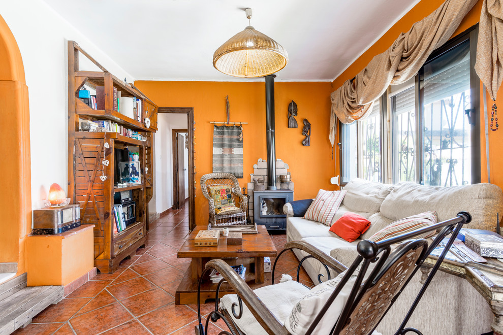 Imagen de salón tropical con parades naranjas, televisor independiente y suelo marrón