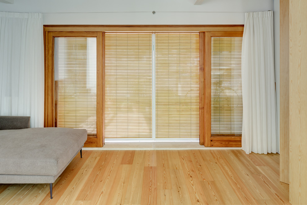Imagen de salón abierto actual con suelo de madera clara