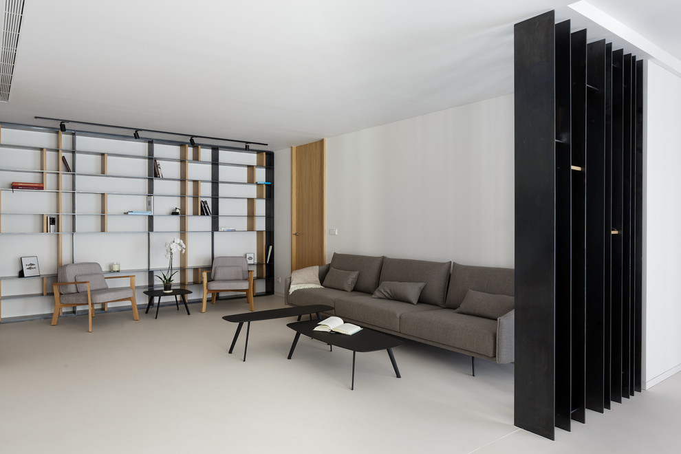 Foto di un soggiorno moderno stile loft con libreria, pareti bianche, pavimento in cemento, TV a parete e pavimento bianco