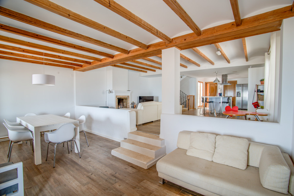 Imagen de salón abierto actual con paredes blancas, suelo de madera en tonos medios, suelo marrón y vigas vistas