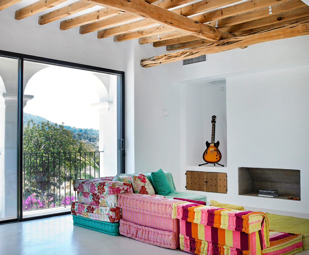 Mediterranes Wohnzimmer mit weißer Wandfarbe, Betonboden, Kamin und grauem Boden in Sonstige