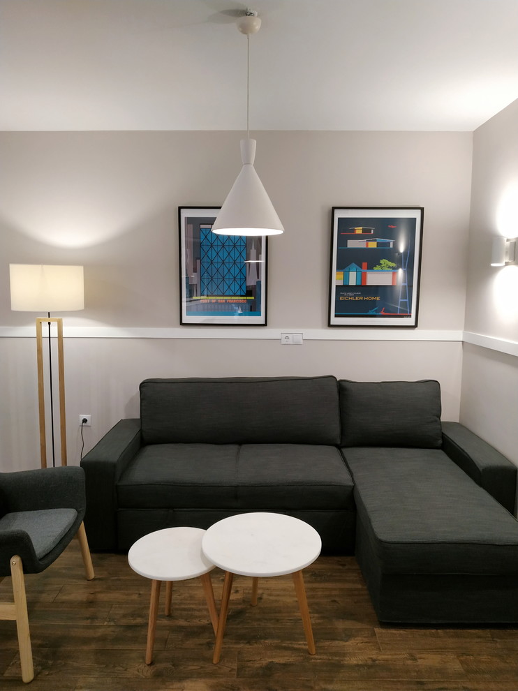 Пример оригинального дизайна: маленькая открытая гостиная комната с серыми стенами, полом из керамической плитки, стандартным камином, фасадом камина из камня, телевизором на стене и коричневым полом для на участке и в саду