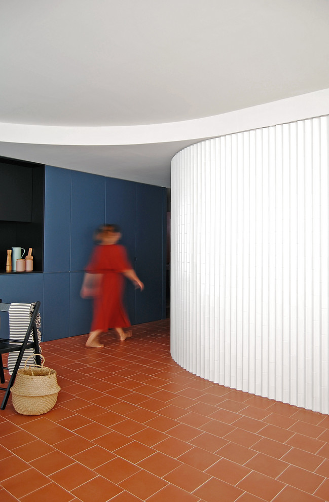 Esempio di un soggiorno moderno di medie dimensioni e aperto con pareti bianche, pavimento in terracotta, nessun camino, TV a parete e pavimento marrone