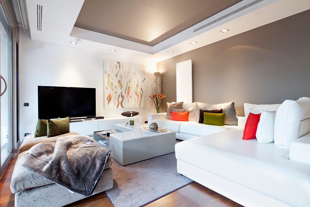 Inredning av ett modernt stort separat vardagsrum, med mellanmörkt trägolv, en fristående TV och flerfärgade väggar