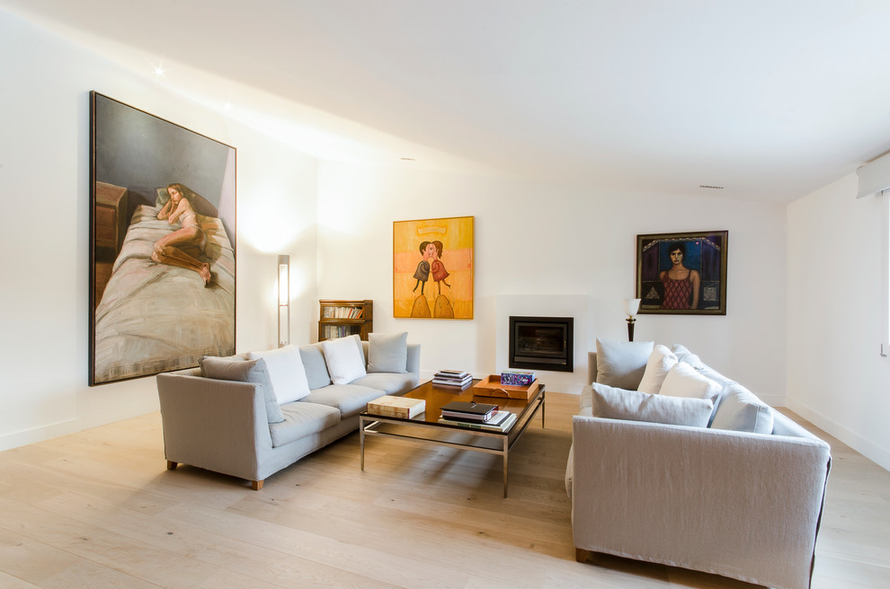 Photo of a large contemporary formal enclosed living room in Madrid with white walls, light hardwood flooring, a standard fireplace, a plastered fireplace surround and no tv.