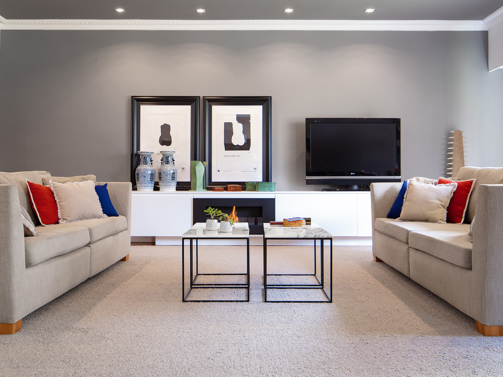 Imagen de salón abierto ecléctico de tamaño medio con paredes grises, moqueta, chimenea lineal, marco de chimenea de metal, televisor independiente y suelo gris