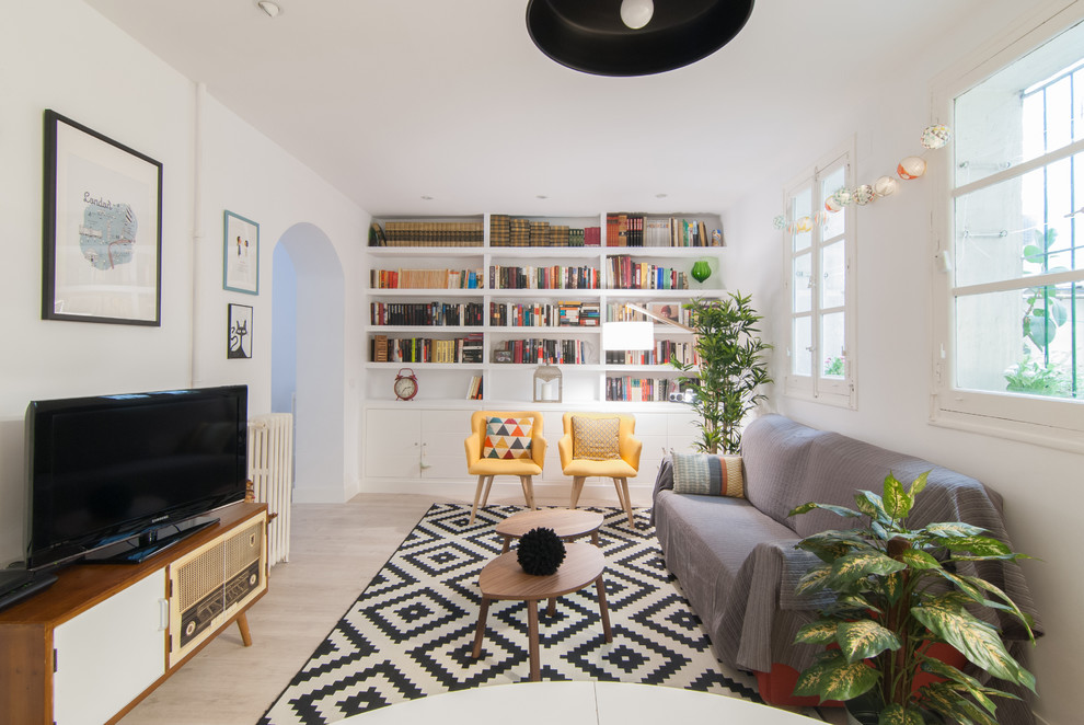 Diseño de biblioteca en casa abierta nórdica de tamaño medio sin chimenea con paredes blancas, suelo de madera clara, pared multimedia y suelo beige
