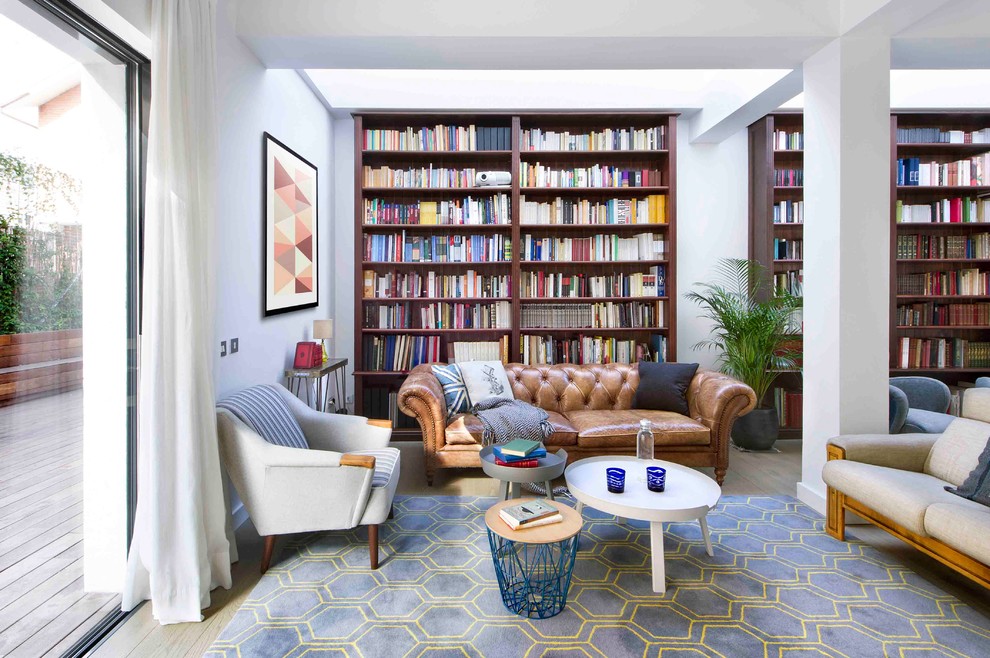 Immagine di un soggiorno minimalista di medie dimensioni e aperto con libreria, pareti bianche, pavimento in legno massello medio, nessun camino e nessuna TV