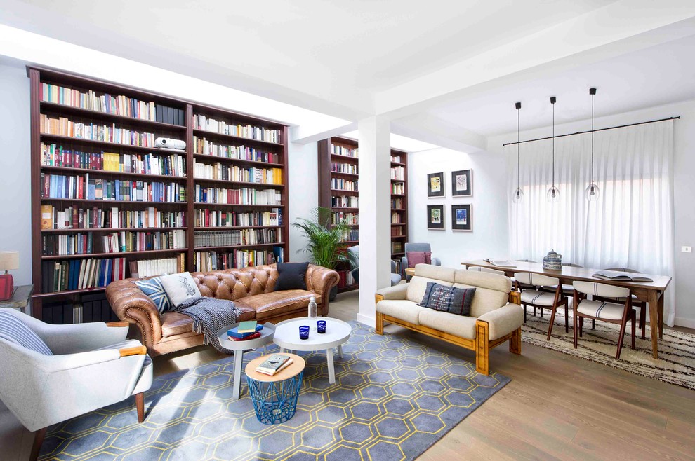 Esempio di un soggiorno minimalista di medie dimensioni e aperto con libreria, pareti bianche, pavimento in legno massello medio, nessun camino e nessuna TV