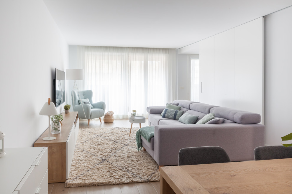 This is an example of a large scandinavian open plan living room in Madrid with white walls, ceramic flooring, no fireplace, a wall mounted tv and brown floors.