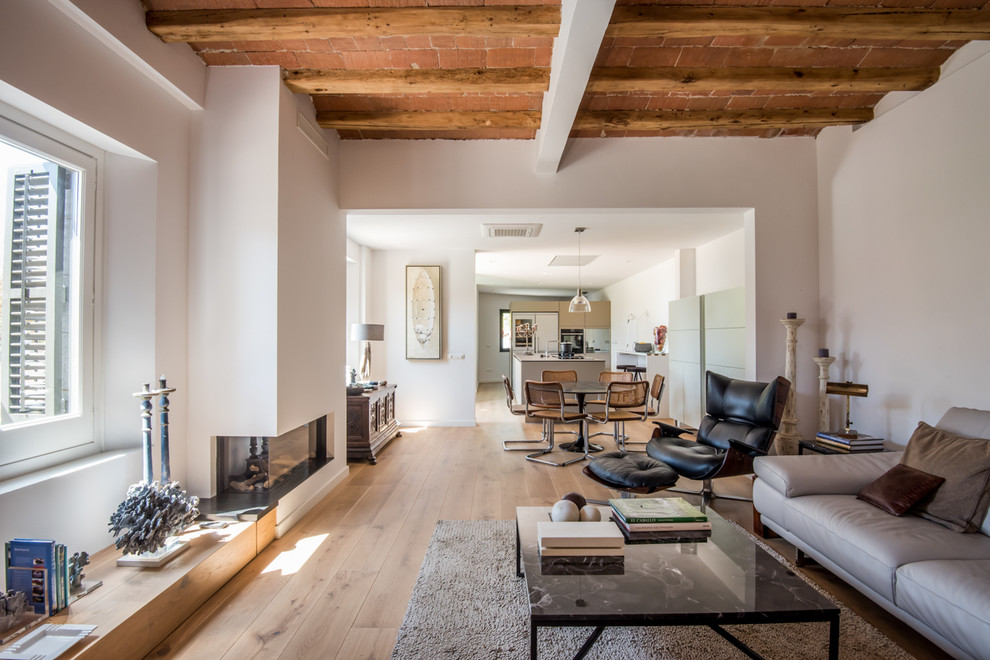 Photo of a large contemporary open plan living room in Barcelona with white walls, medium hardwood flooring, a corner fireplace, a plastered fireplace surround, no tv and feature lighting.
