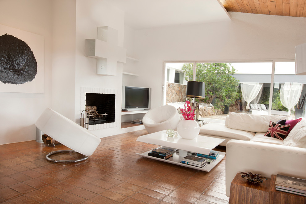 Immagine di un grande soggiorno mediterraneo aperto con sala formale, pareti bianche, pavimento con piastrelle in ceramica, camino classico e TV autoportante