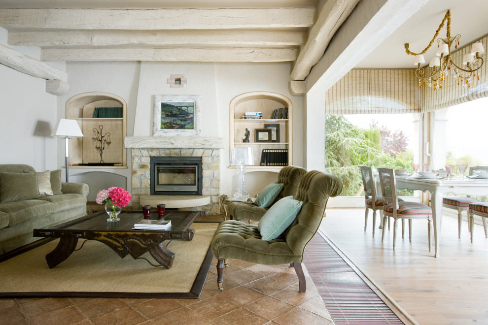 Immagine di un grande soggiorno mediterraneo aperto con sala formale, pareti bianche, camino classico, cornice del camino in pietra e pavimento beige