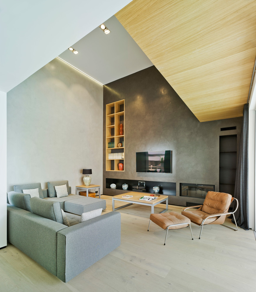 Diseño de salón abierto minimalista grande con paredes grises, suelo de madera clara, televisor colgado en la pared, chimenea lineal y suelo beige