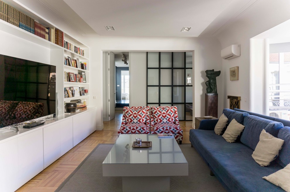 Стильный дизайн: открытая гостиная комната среднего размера в стиле модернизм с белыми стенами, светлым паркетным полом, отдельно стоящим телевизором, бежевым полом и синим диваном - последний тренд