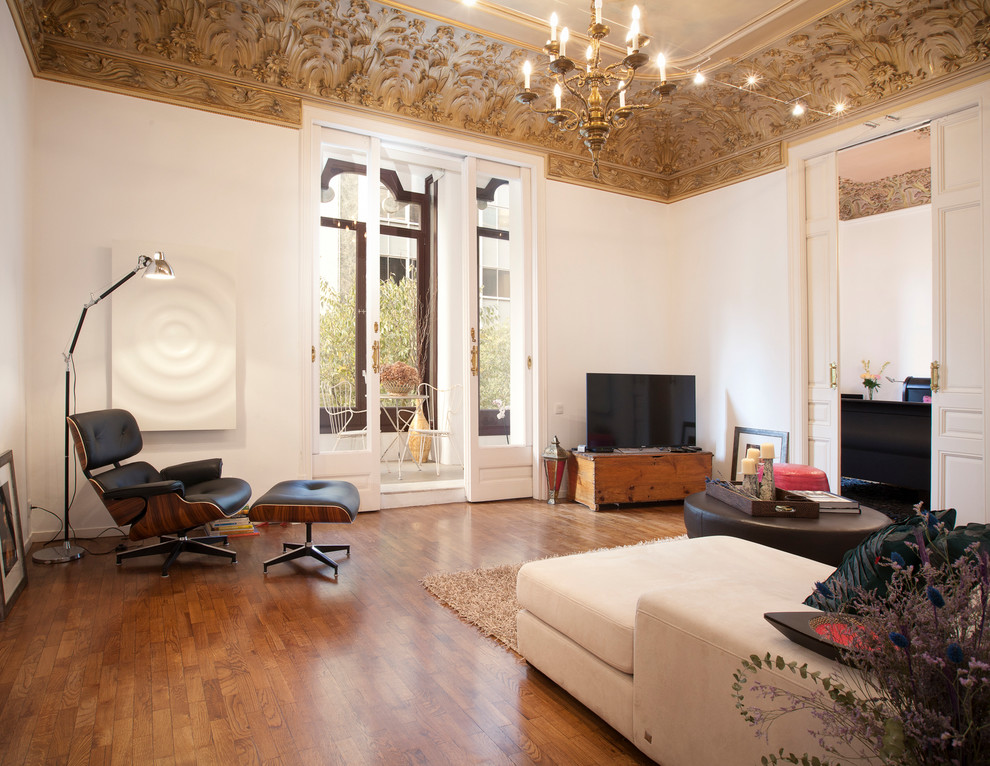 Eklektisk inredning av ett stort separat vardagsrum, med ett finrum, vita väggar, mellanmörkt trägolv och en fristående TV