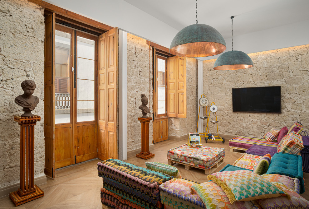 Imagen de salón bohemio con paredes beige, suelo de madera clara, televisor colgado en la pared y suelo beige