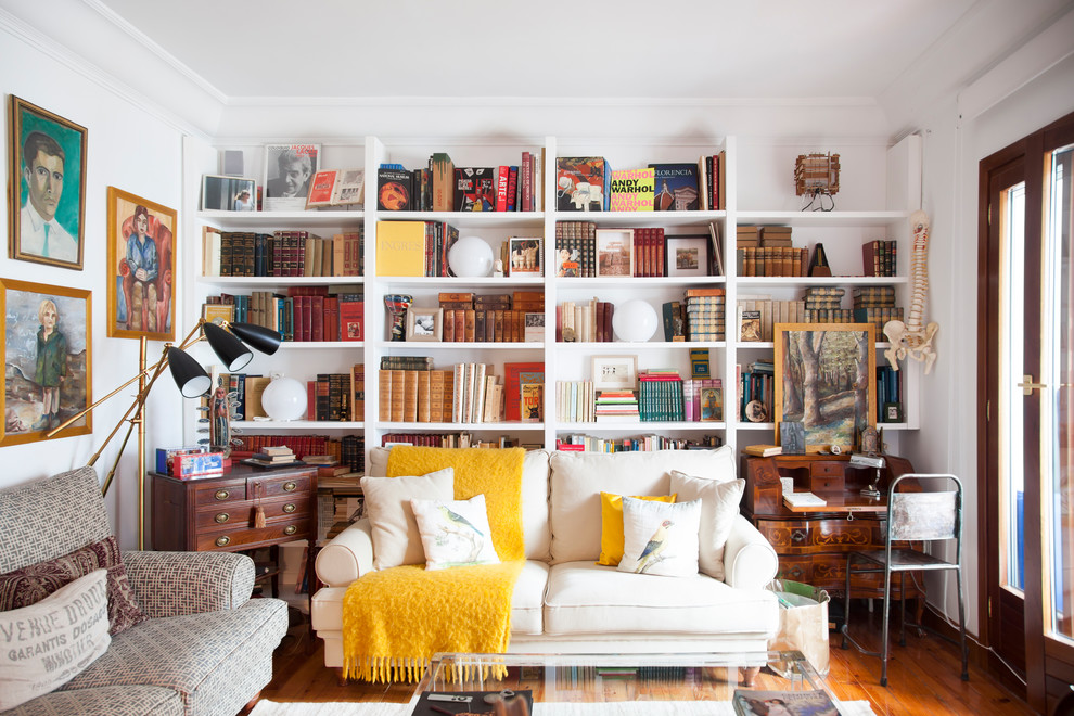 Idee per un piccolo soggiorno boho chic con libreria, pareti bianche e pavimento in legno massello medio