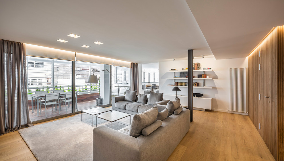 Diseño de salón abierto actual de tamaño medio con paredes blancas, suelo de madera en tonos medios, televisor independiente y suelo marrón