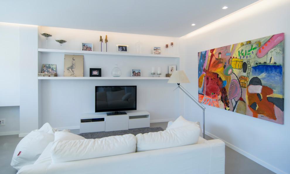 Foto de salón contemporáneo con paredes blancas, suelo de cemento, televisor independiente y suelo gris
