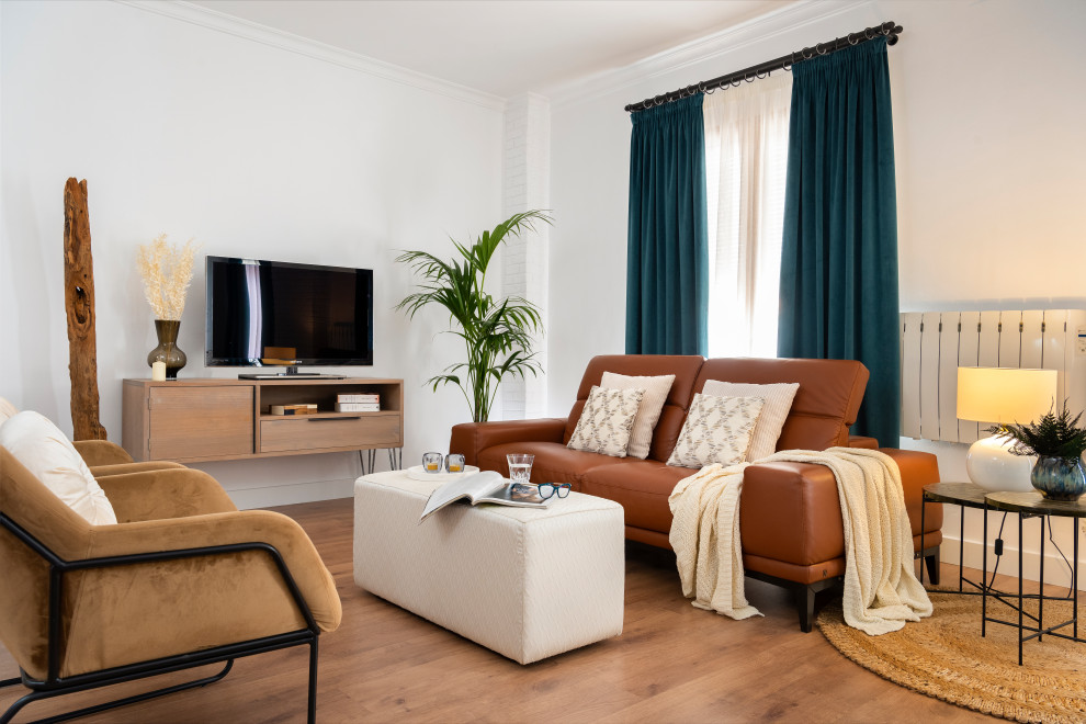 Modelo de salón abierto actual con paredes blancas, suelo de madera en tonos medios, televisor independiente y suelo marrón