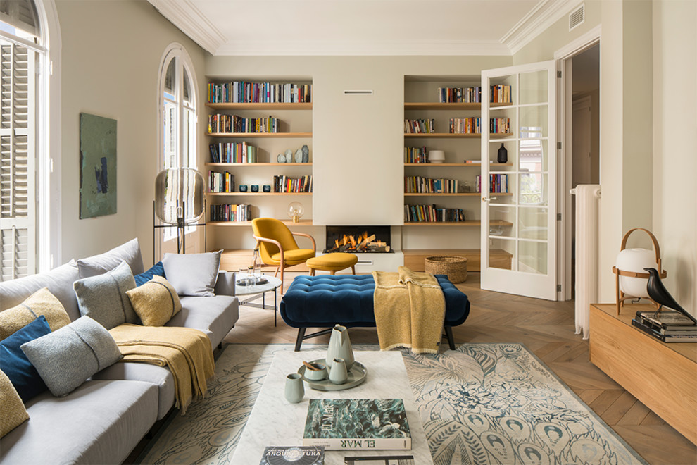 Ejemplo de biblioteca en casa cerrada mediterránea grande sin televisor con paredes beige, suelo de madera en tonos medios, estufa de leña, marco de chimenea de yeso y suelo beige