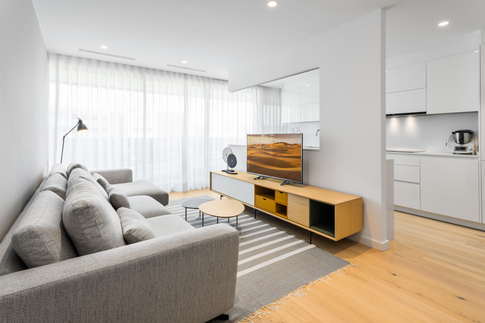 Idéer för ett modernt allrum med öppen planlösning, med vita väggar, ljust trägolv, en fristående TV och beiget golv