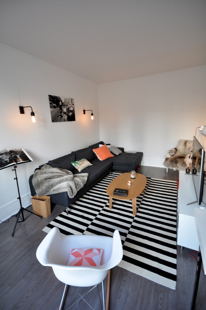Exemple d'un salon tendance de taille moyenne et fermé avec un mur blanc, un sol en bois brun, un téléviseur indépendant et un sol gris.
