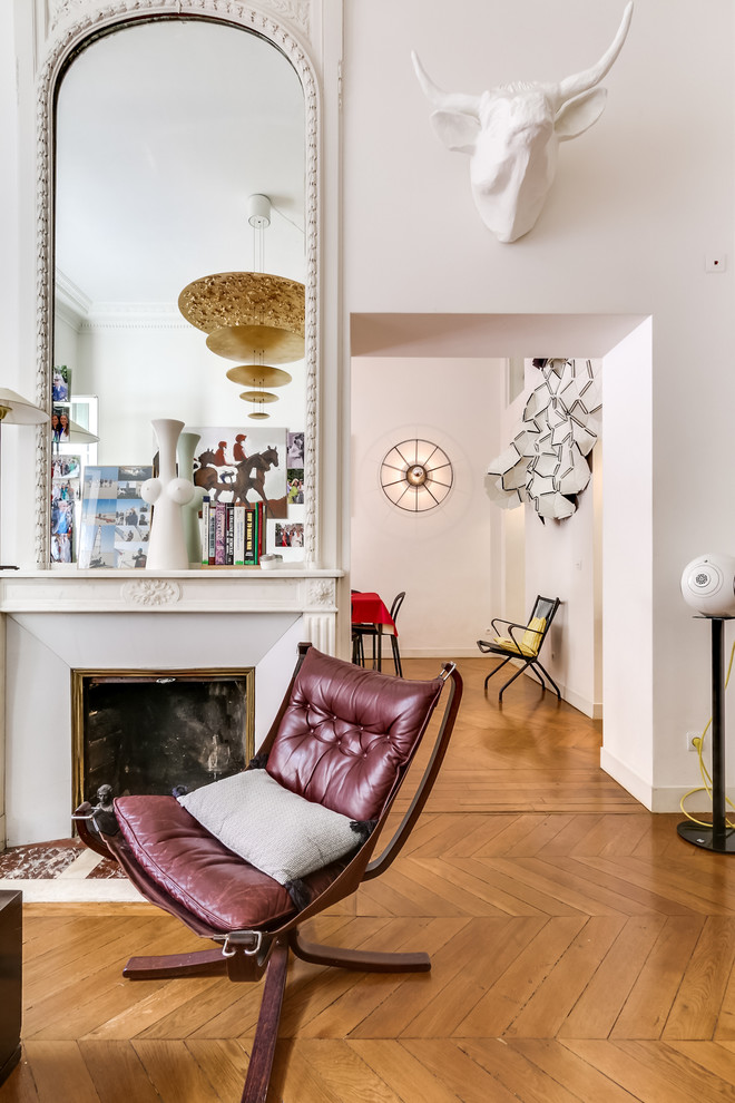 Fernseherloses, Offenes Stilmix Wohnzimmer mit rosa Wandfarbe, braunem Holzboden, Kamin und verputzter Kaminumrandung in Paris